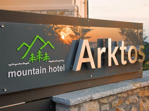 The Arktos mountain hotel sign on a stone wall